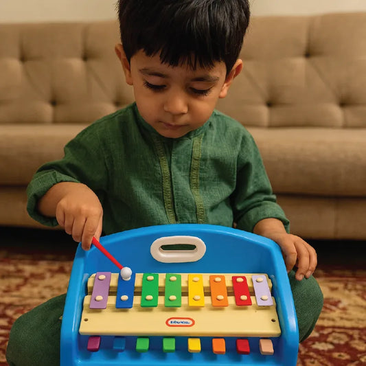 Child playing with a colorful toy keyboard in a living room setting.