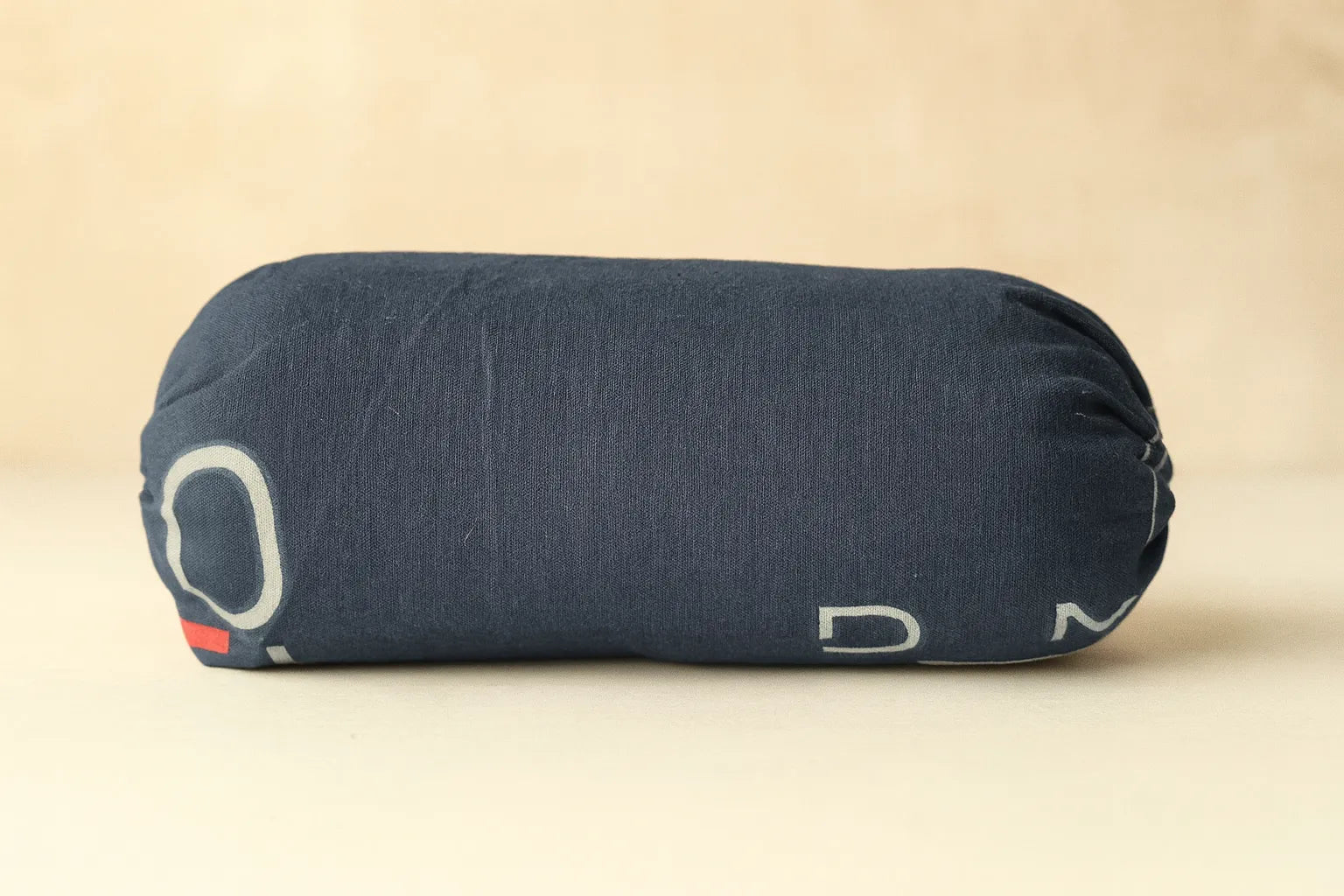 Blue cylindrical pillow with brand logo on a beige background