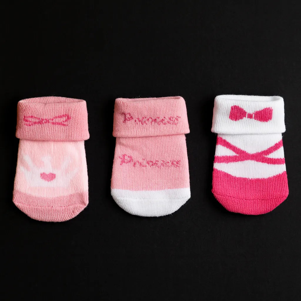 Three pairs of pink baby socks with 'Princess' and ballet design on a black background
