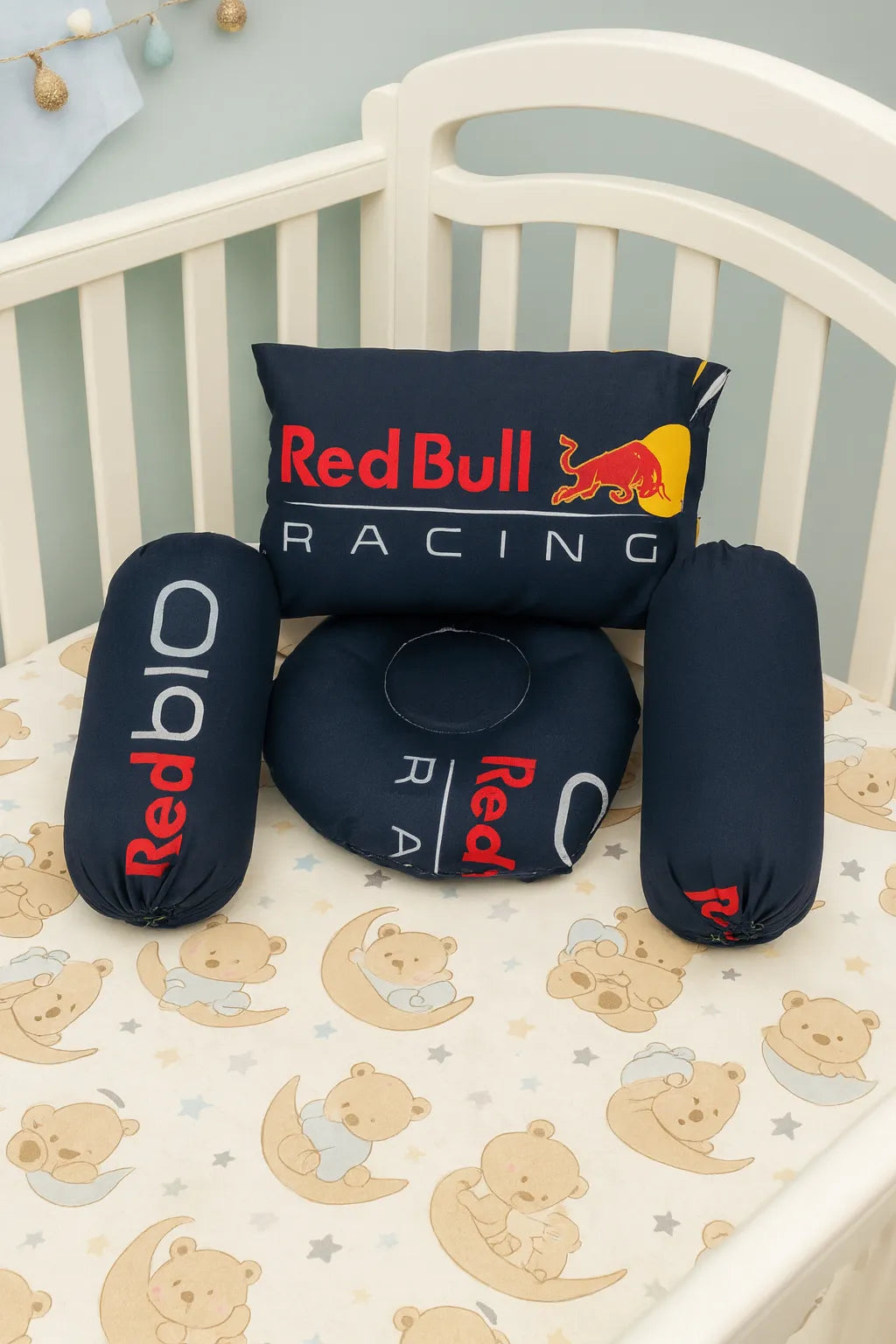 Red Bull Racing pillows on a crib with a patterned sheet