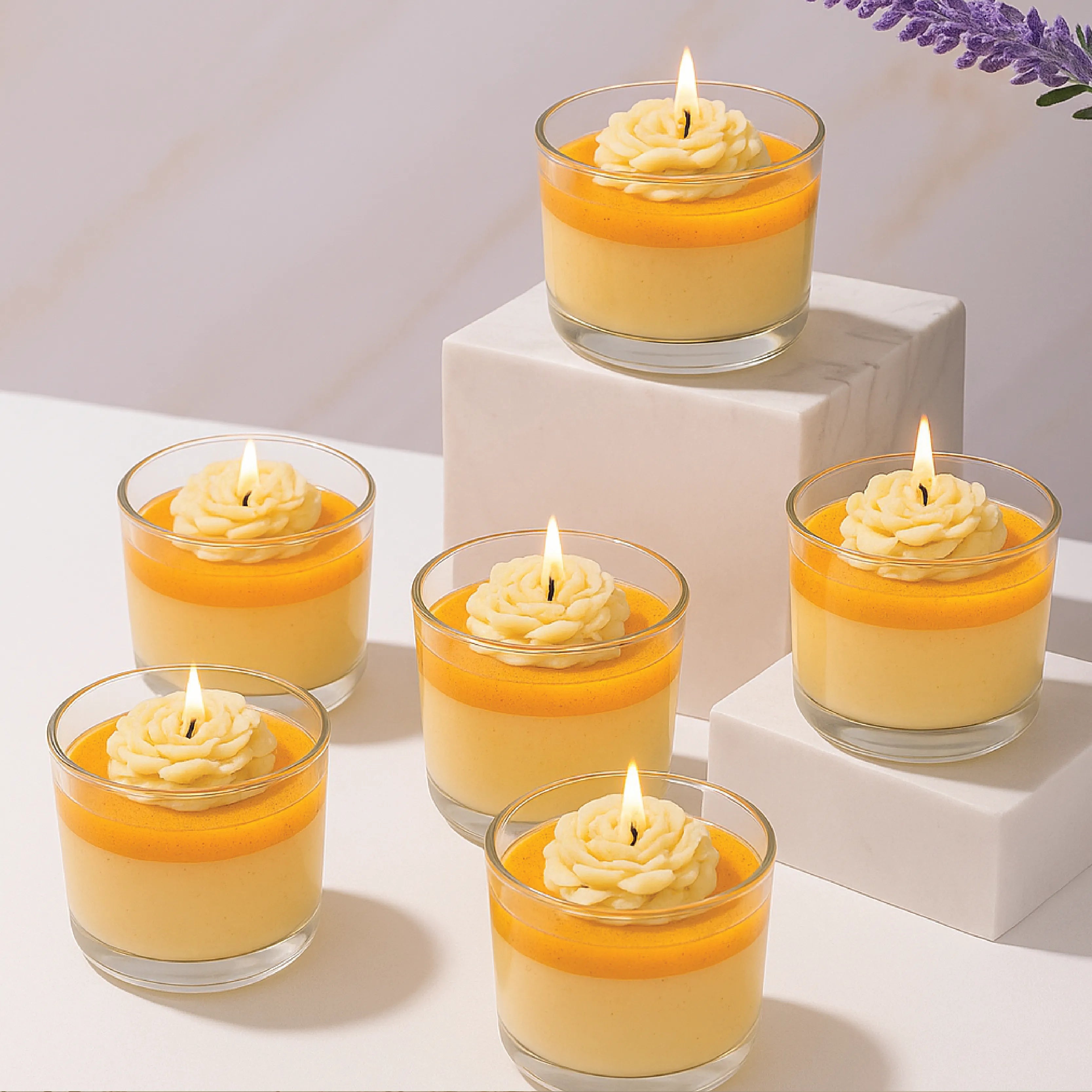 Set of six small glass jars with yellow candle melts and lit candles on a white surface.